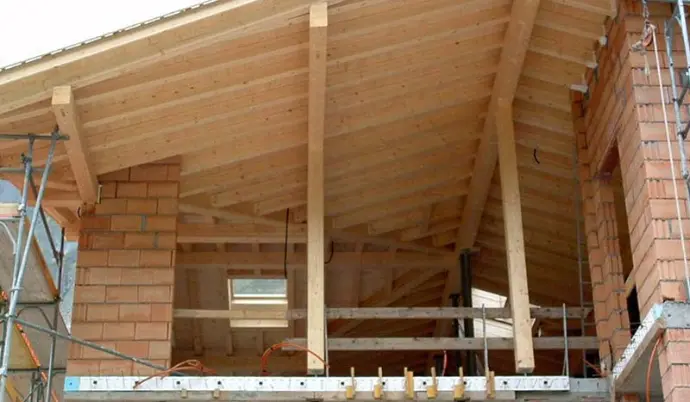 Holz-Dachstuhl im Bau, mit Ziegelwänden und Gerüst.