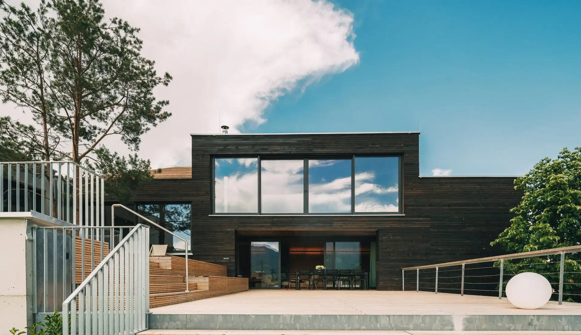 Modernes Haus mit dunkler Holzfassade, großen Fenstern und Terrasse  über Pfunds