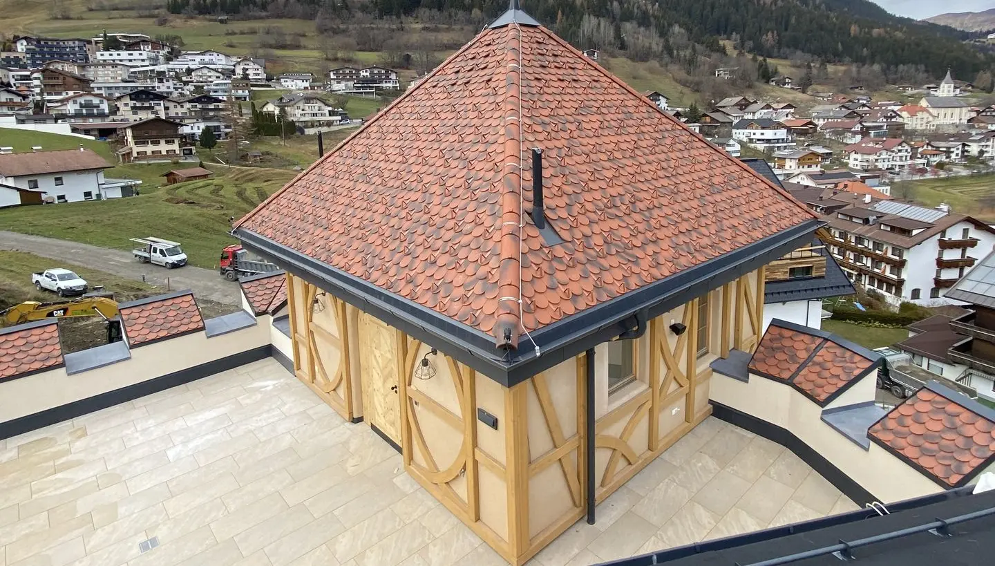 Turmähnliches Gebäude mit Fachwerkelementen und Ziegeldach, umgeben von einer Terrasse mit Blick auf Pfunds